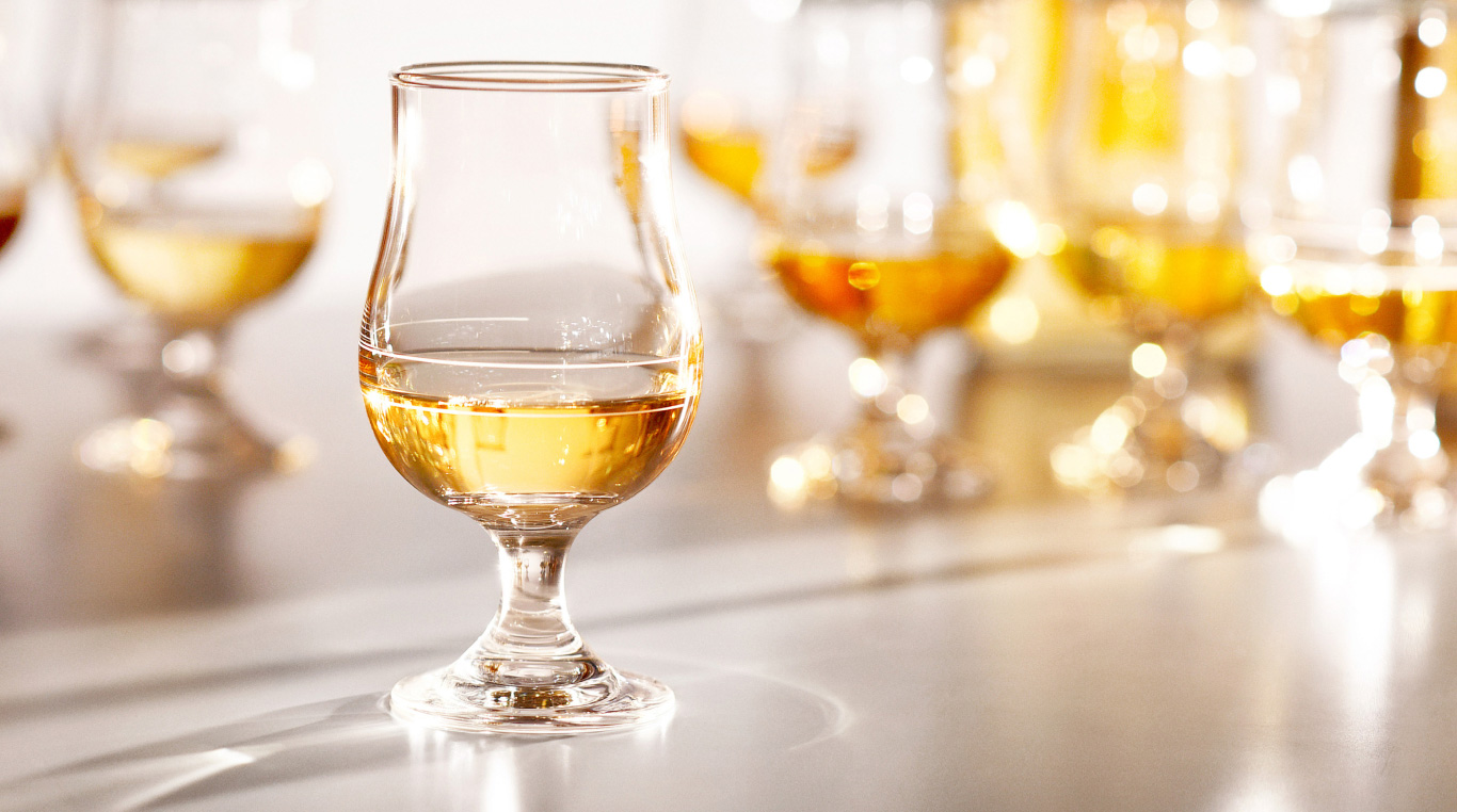 A glass of whiskey with multiple out-of-focus glasses in the background.
