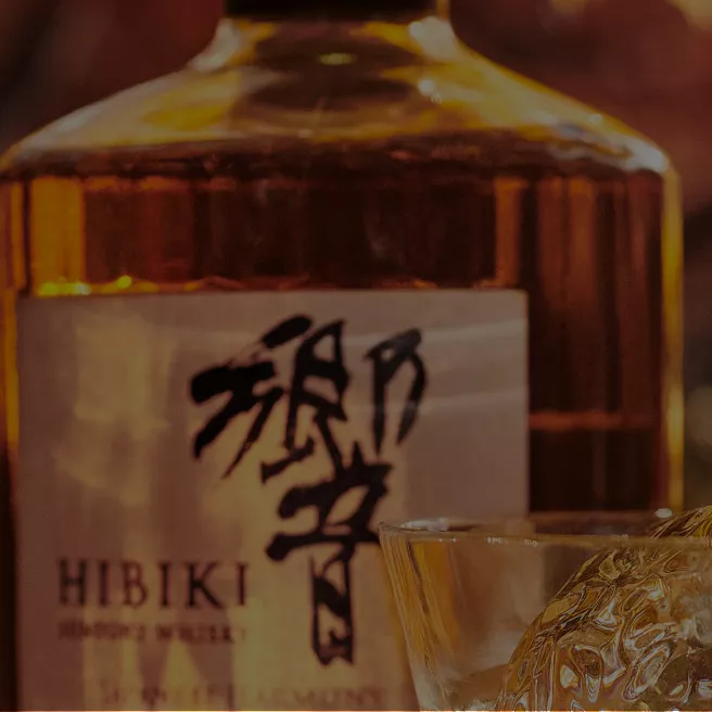 A glass of Hibiki whisky on ice in front of a bottle of Hibiki whisky