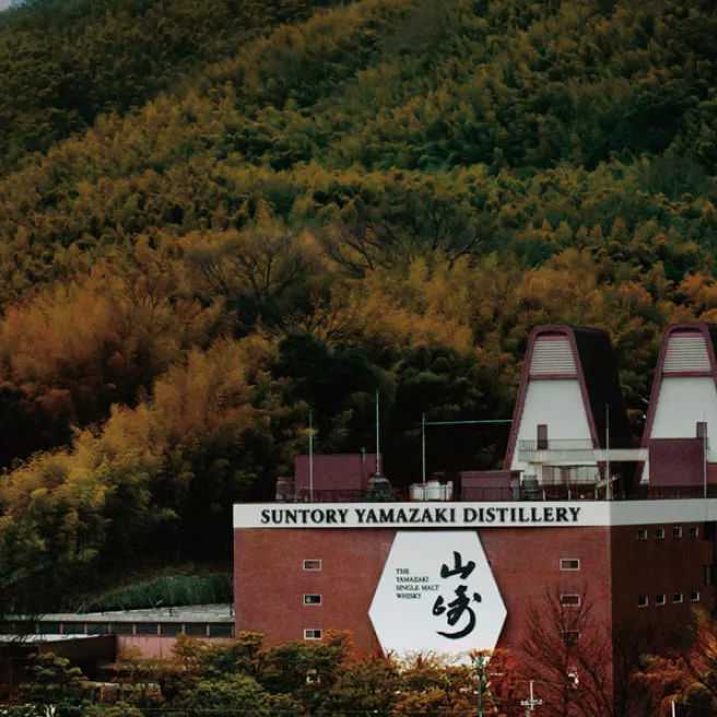 Yamazaki Distillery with two twin spire roof among fall leaves on the hillsides of Japan