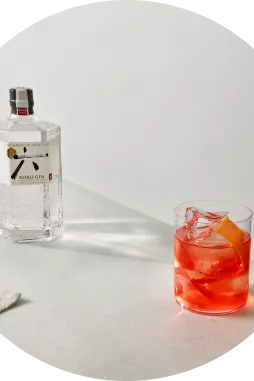 Red Roku Gin Negroni cocktail next two bottle of Roku gin