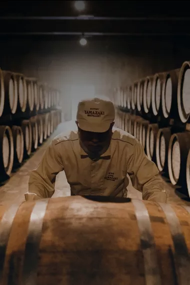 Yamazaki Distillery employee rolling an oak barrel of whisky