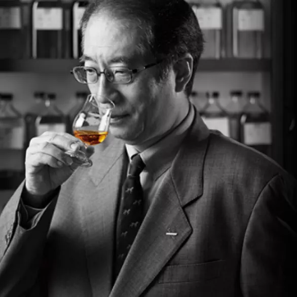 Black and white photo of a Japanese man, smelling a whisky glass of House of Suntory