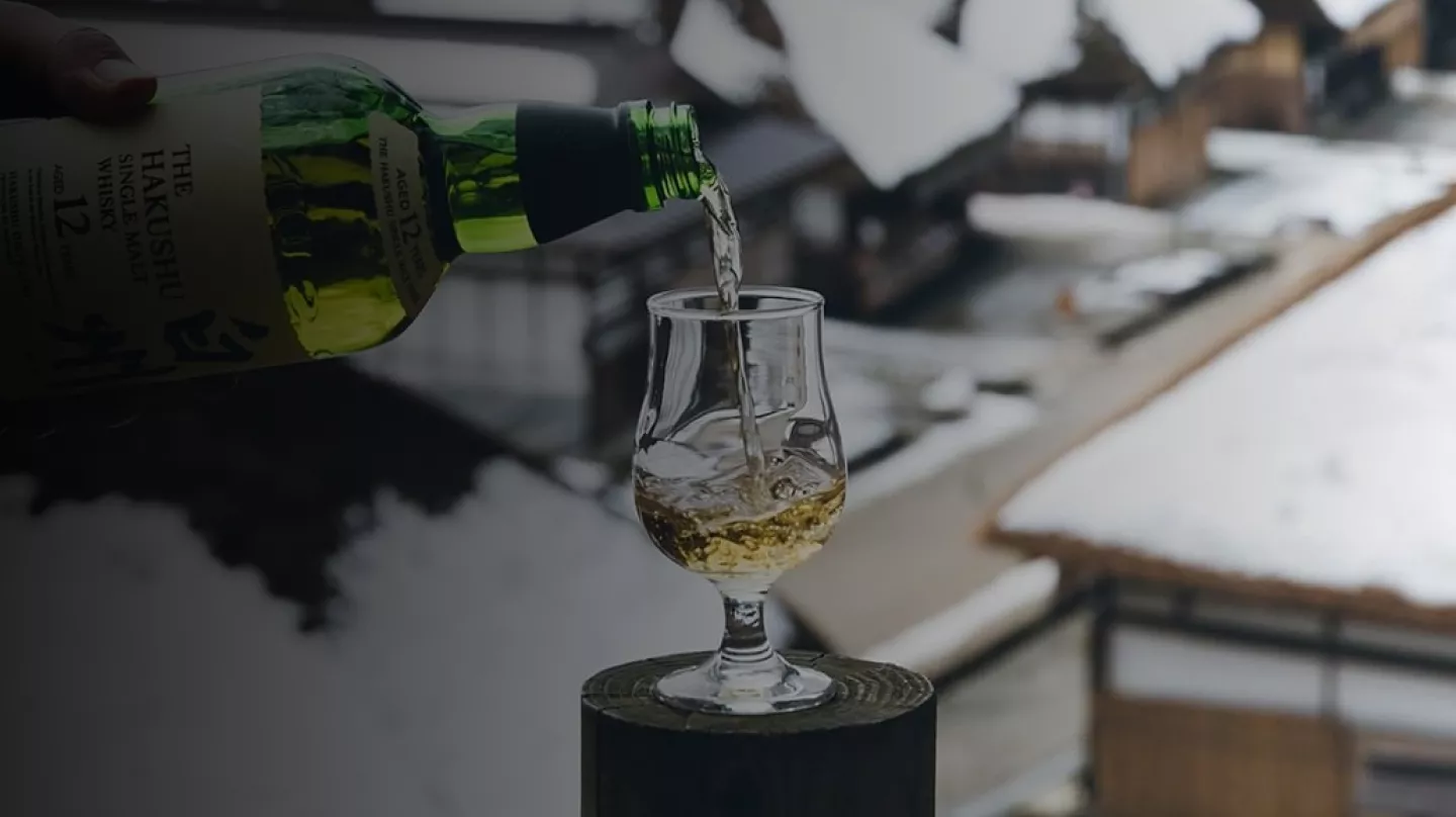 Green bottle pouring Suntory Hakushu Whisky into a tulip glass