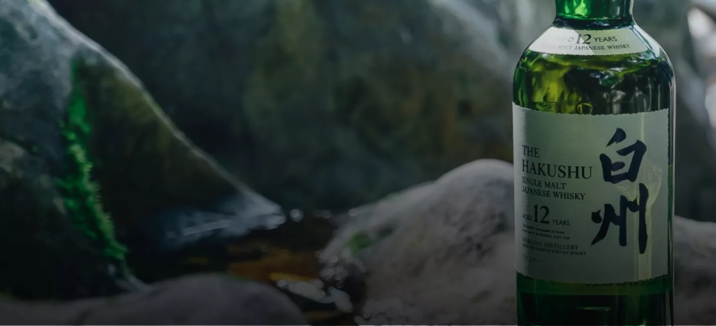 Green bottle of Suntory Hakushu Whisky sitting on gray rocks