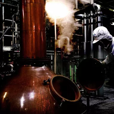 Person crafting Japanese gin in a copper pot at Osaka distillery