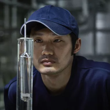 Man looking at beaker of clear Japanese spirits
