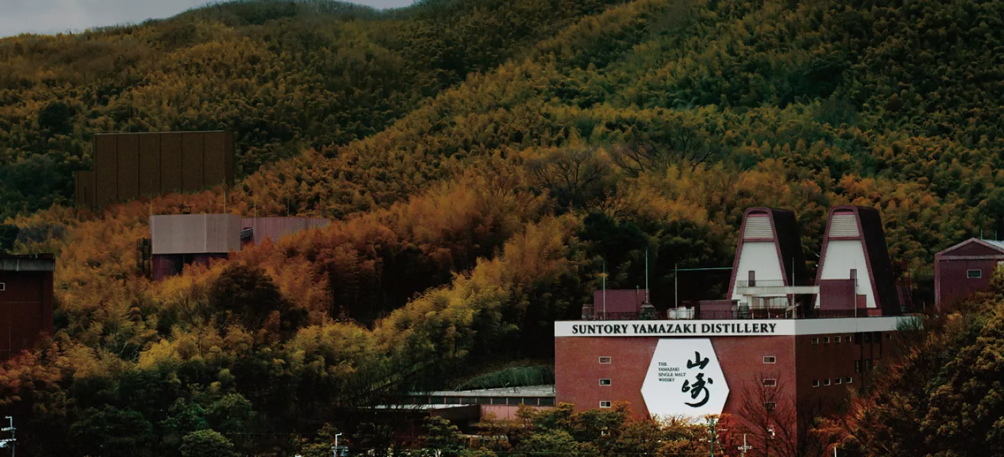 Yamazaki Distillery with two twin spire roof among fall leaves on the hillsides of Japan