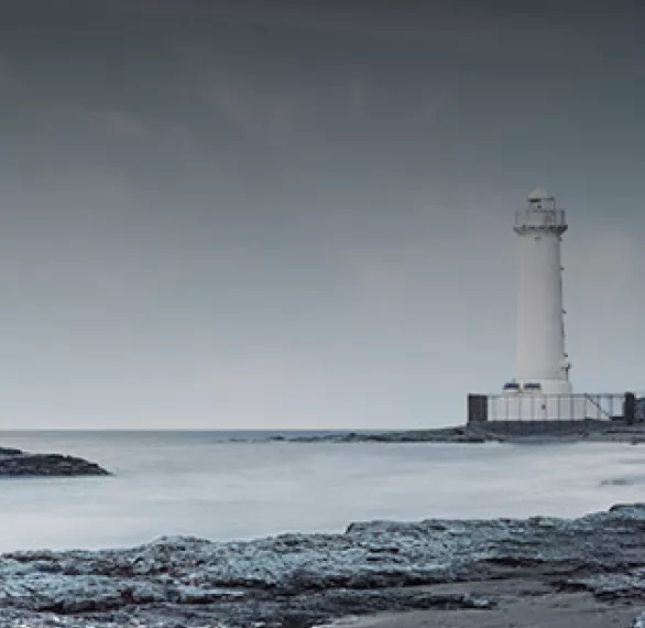 White lighthouse on the rocks by a gray sea
