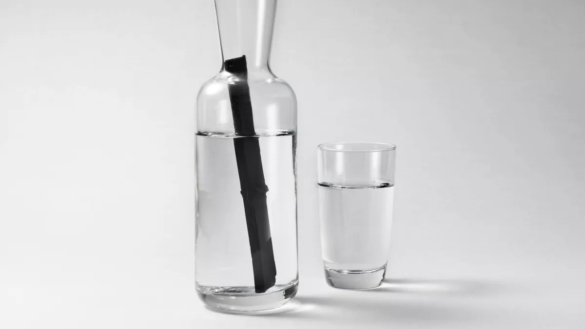 Clear glass pitcher of Suntory Haku vodka with a stick of charcoal filter