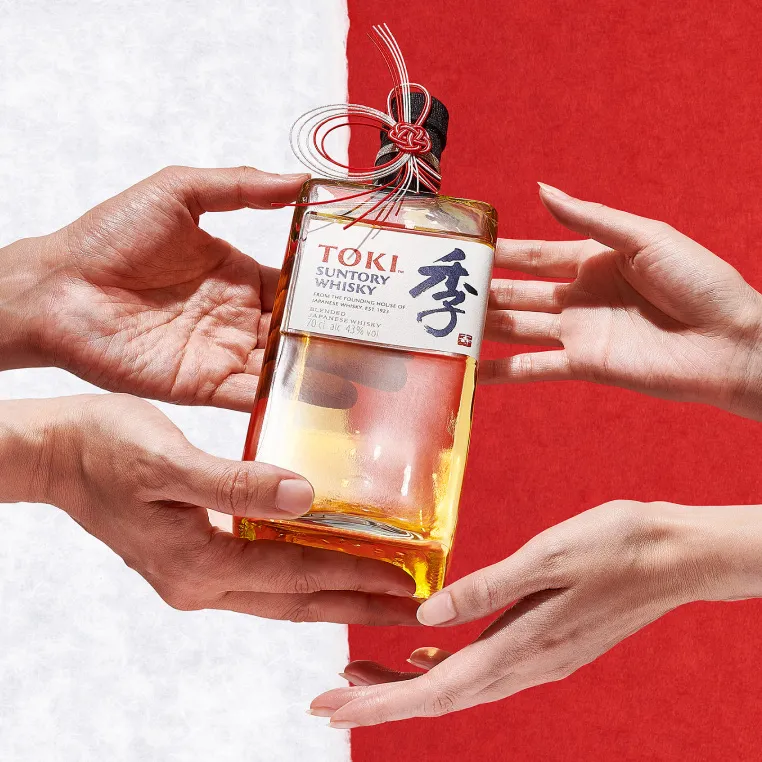 A person giving a bottle of toki to another person.