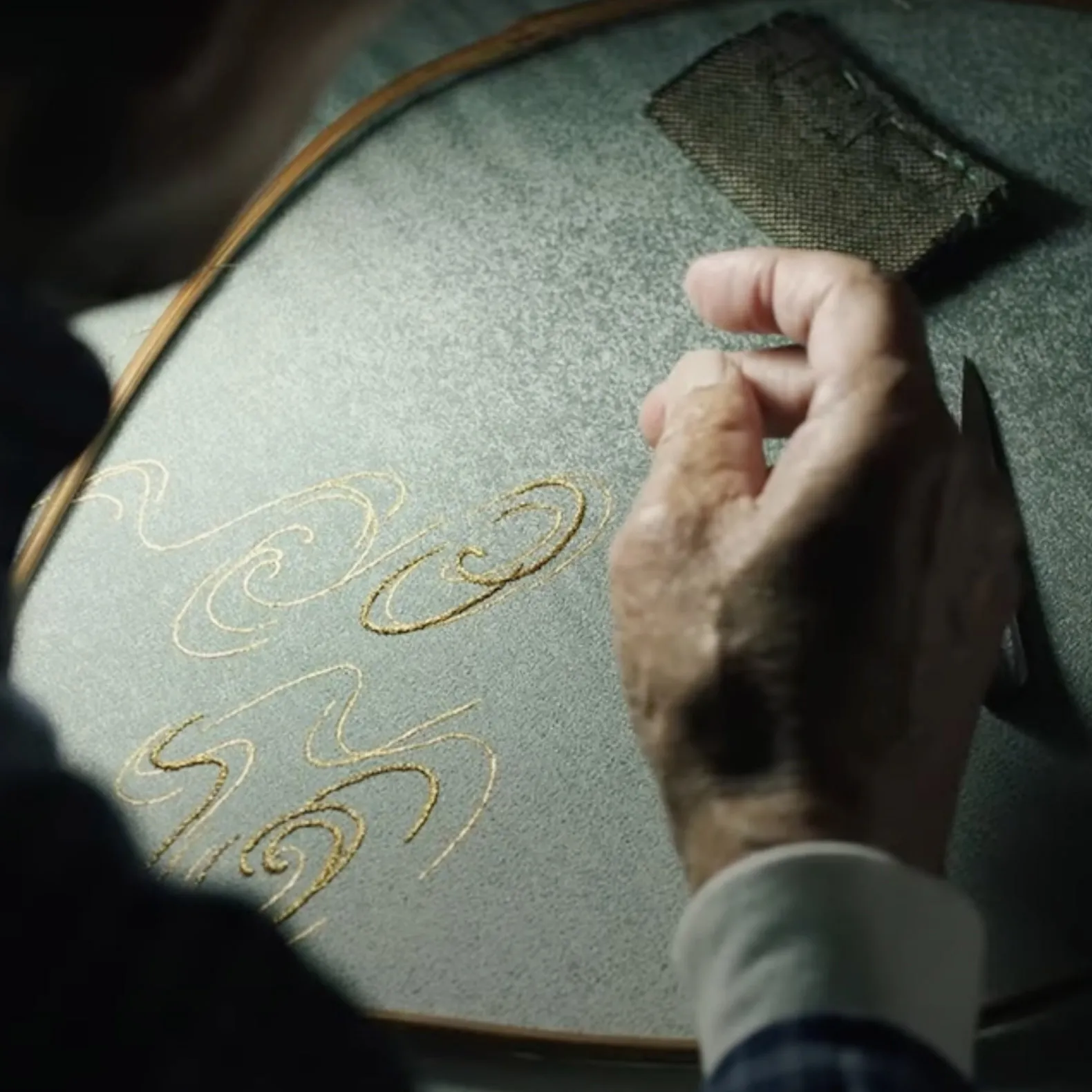 A man creates elegant gold writing on a mirror, showcasing his artistic talent and creativity in a reflective medium.