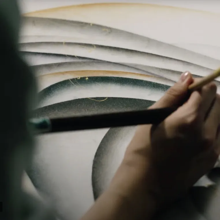 A person skillfully painting with a brush on a clean white background, showcasing creativity and artistic expression.