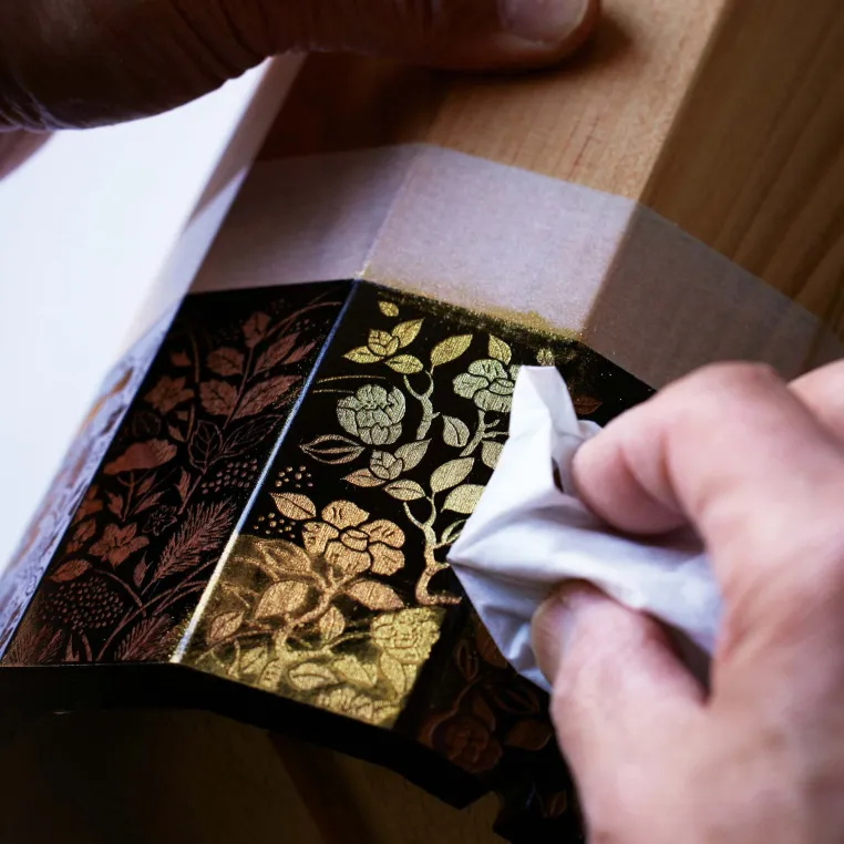A person diligently cleans a wooden surface with a cloth, ensuring it is free of dust and dirt.