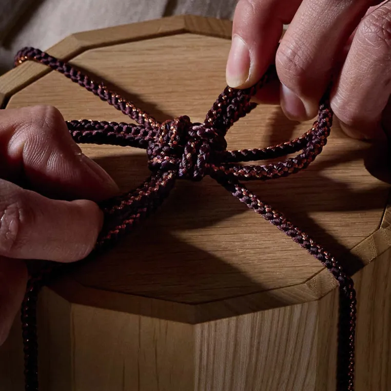 A person skillfully tying a knot on a wooden box, demonstrating attention to detail and craftsmanship.