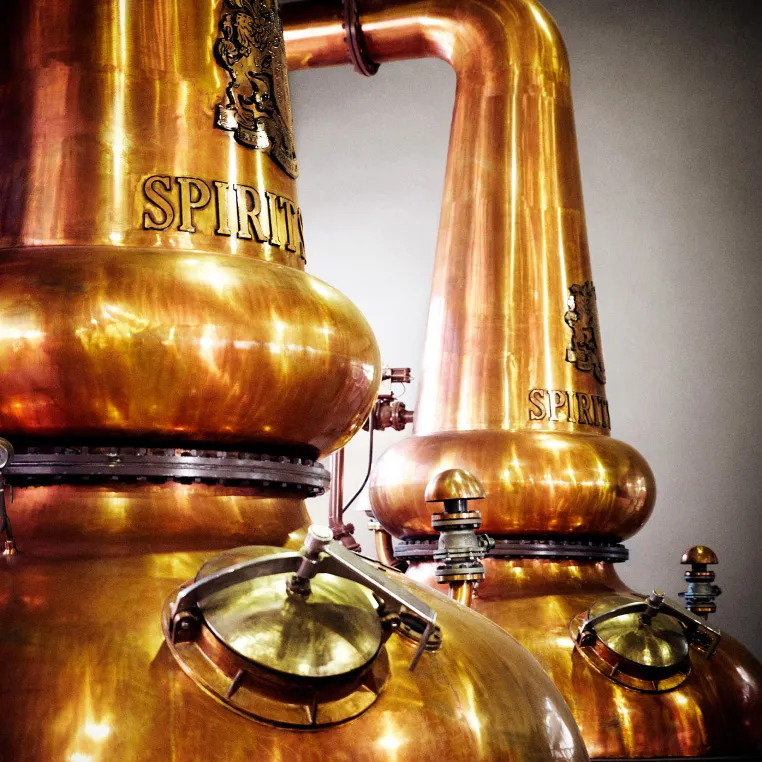 Copper stills with 'Spirit' engraved, used for distillation.