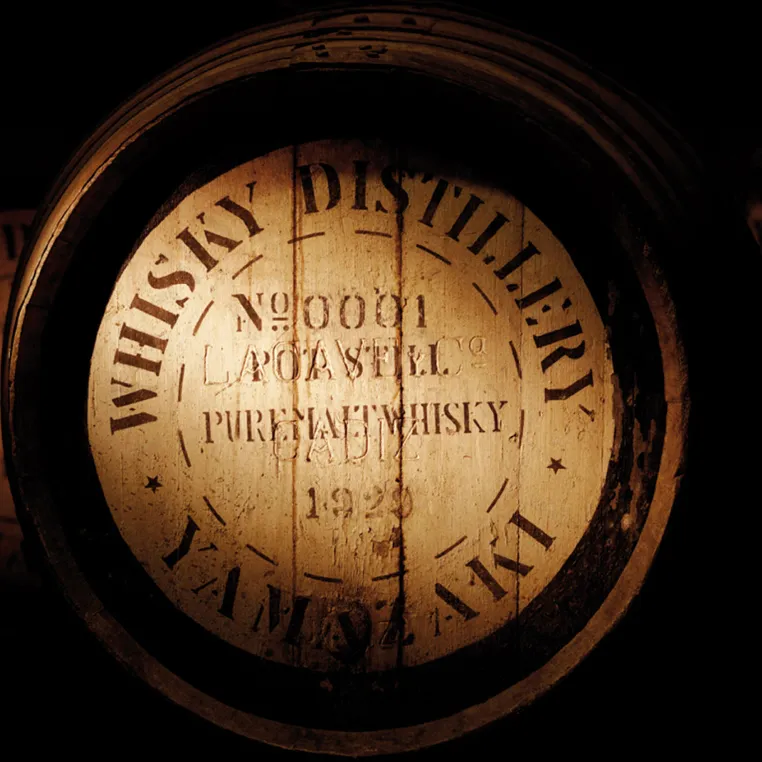 Close-up of a vintage whisky barrel with distillery markings in warm tones.