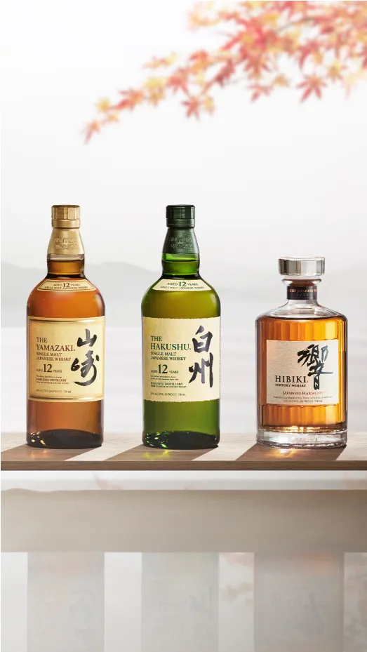 Three bottles of Japanese whisky with autumn leaves in the background.