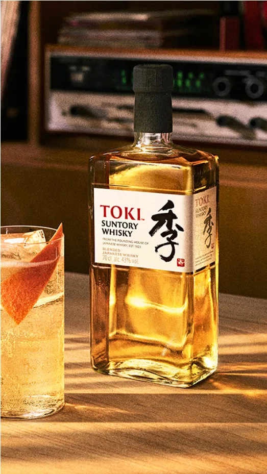 Bottle of Roku Gin on an ice block against a floral background.