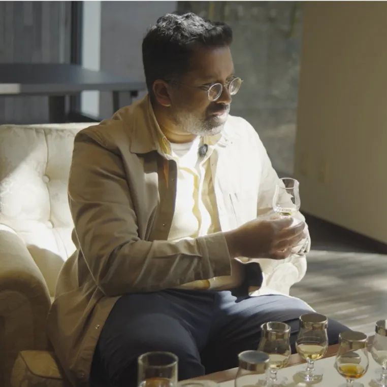 Mr Lyan holding a whisky glass delicately 