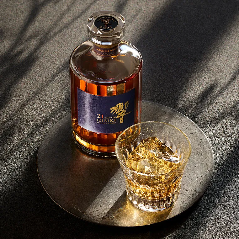 hibiki 21 year old bottle along with whisky glass with whisky on a coaster