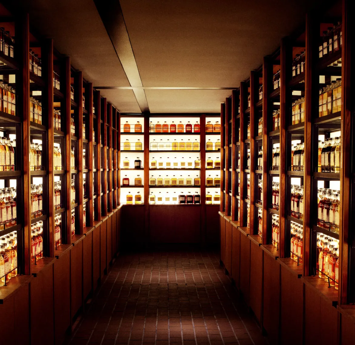 A dimly lit hallway lined with wooden shelves displaying a variety of bottles, highlighting their vibrant colors in warm lighting.