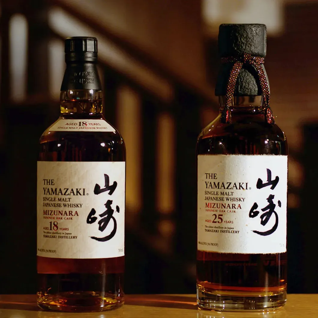 Two bottles of Yamazaki single malt Japanese whisky, one aged 18 years and the other 25 years, displayed elegantly.